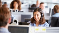Young woman working in call centre, surrounded by colleagues